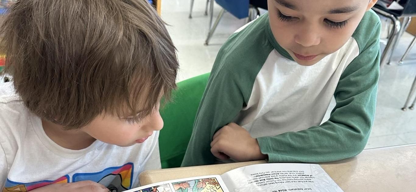 Two young students reading a book together